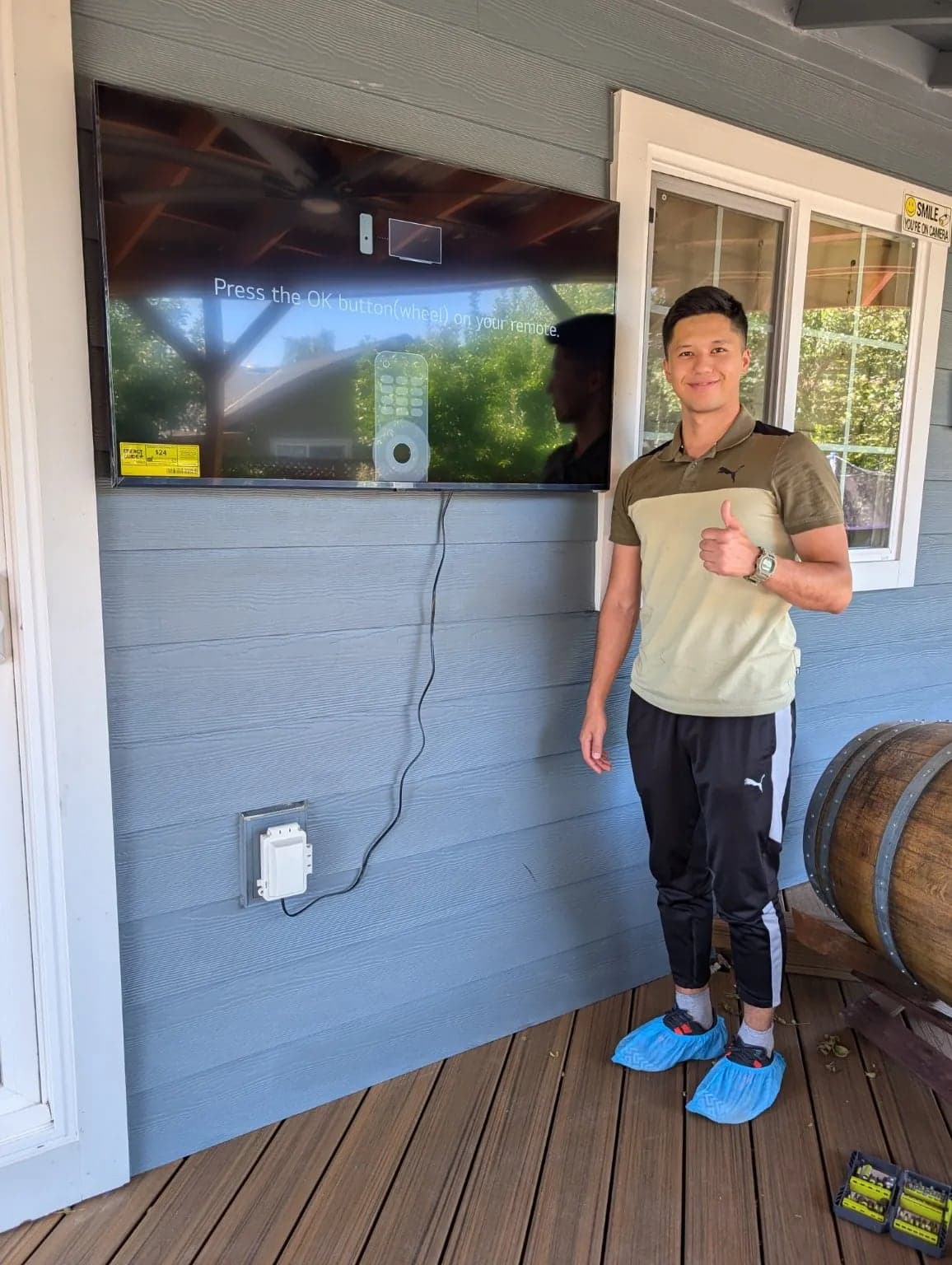 A flat screen TV mounted on the wall of a covered outdoor deck