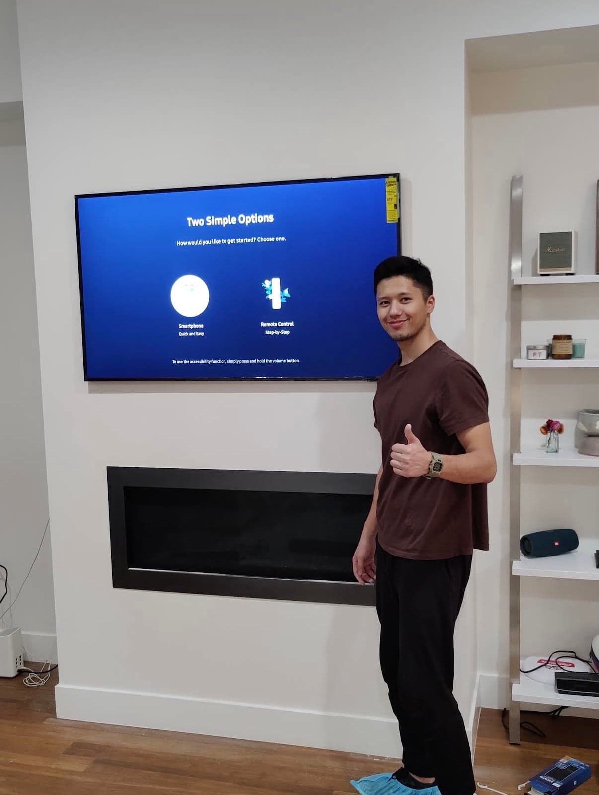 A flat screen TV mounted above a built-in electric fireplace insert in a bright white room