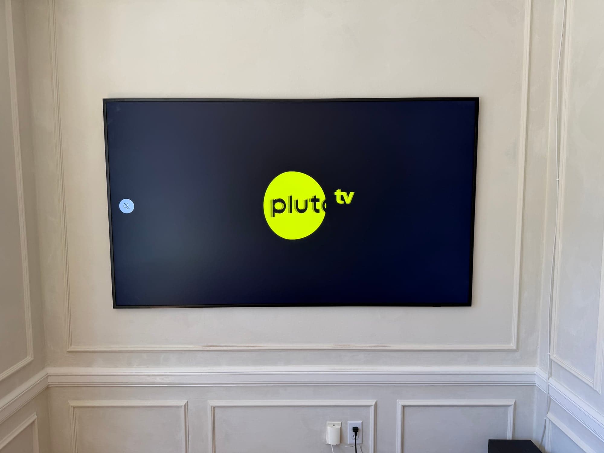 A flat screen TV mounted on a paneled wall with no visible cables