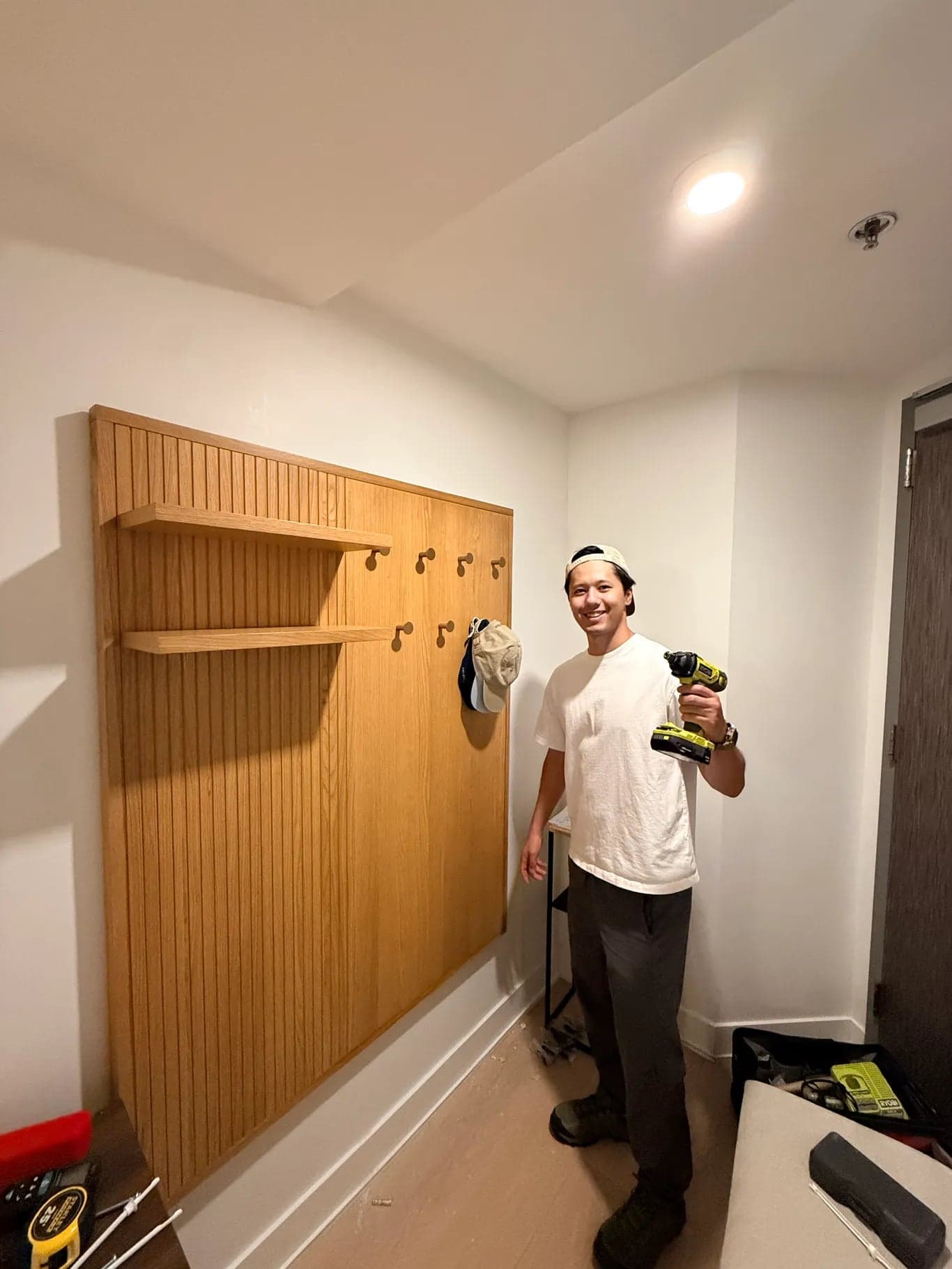 A built-in wood shelving and coat hook wall installed in an entryway